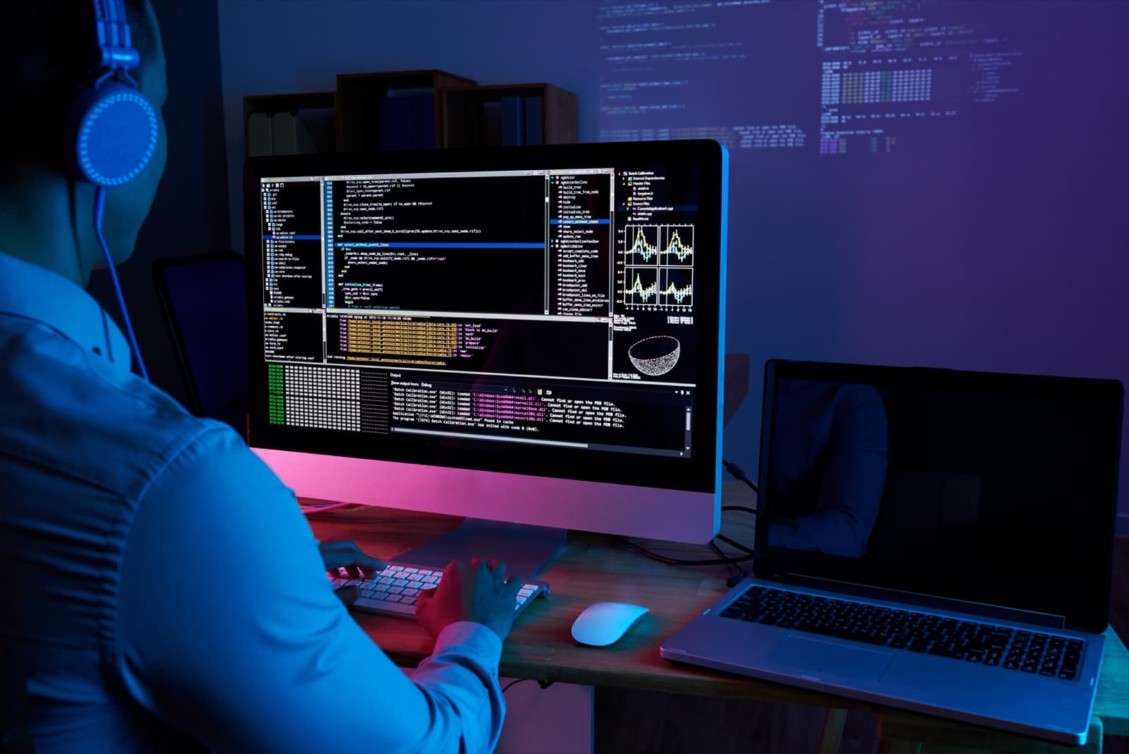 A software engineer reviewing code on screen in a darkened office